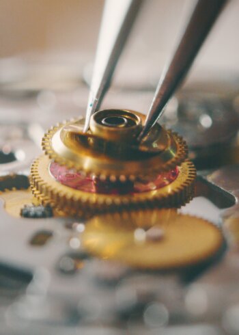 Portrait close up of a professional watchmaker repairer working on a vintage mechanism clock in a workshop.